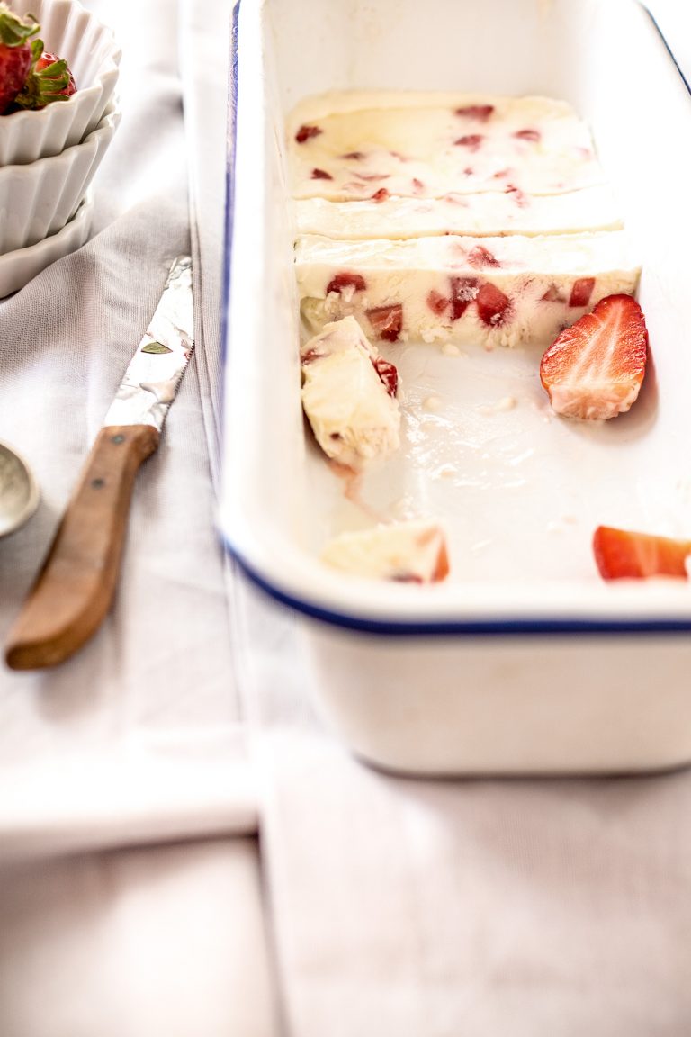 Angeschnittenes Eis mit Erdbeeren und einem Messer daneben